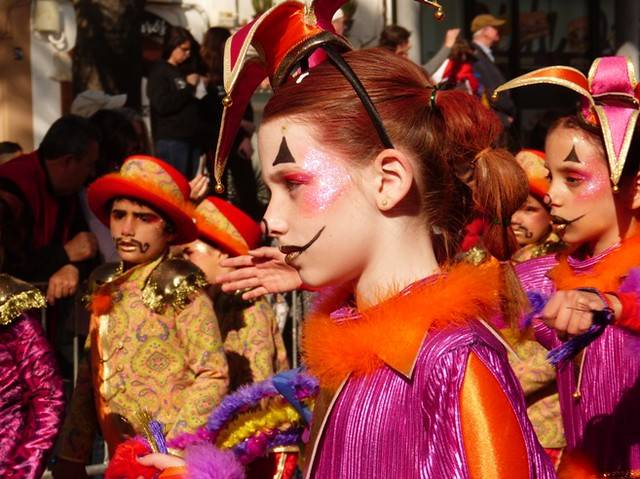 Niños disfrazados en un colorido desfile, con maquillaje y trajes brillantes.