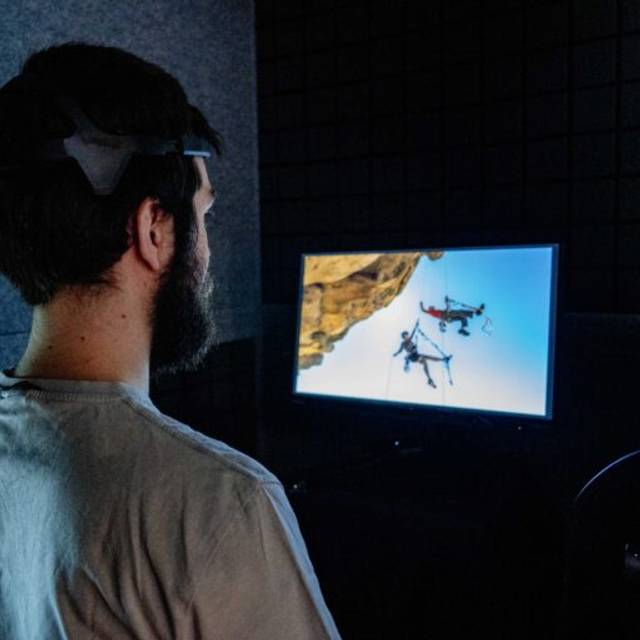 Un hombre observa una pantalla en la que se muestran drones volando cerca de una roca.