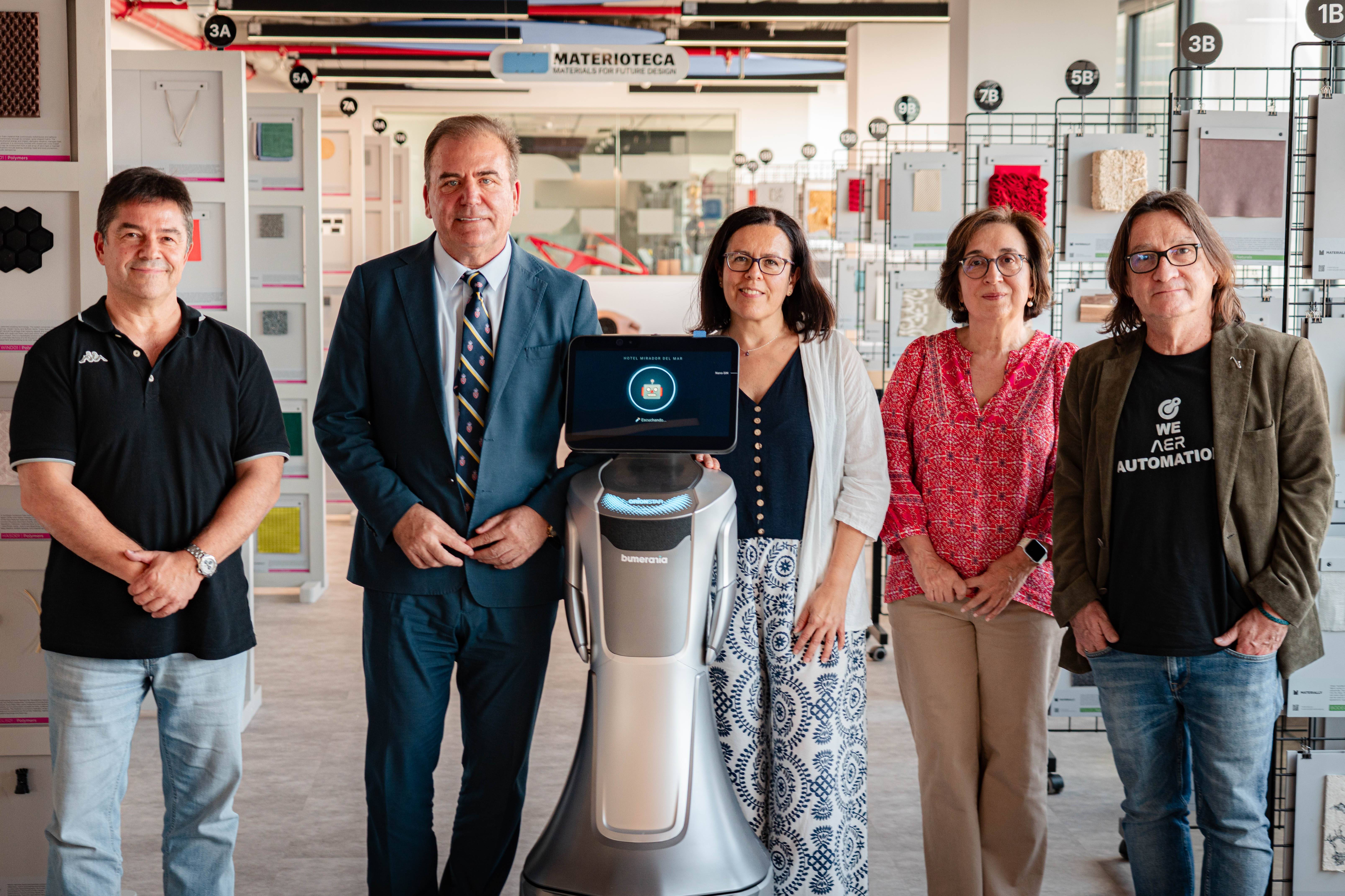 Un grupo de cinco personas, incluidas varias mujeres y un robot, se encuentran en un espacio de trabajo moderno.