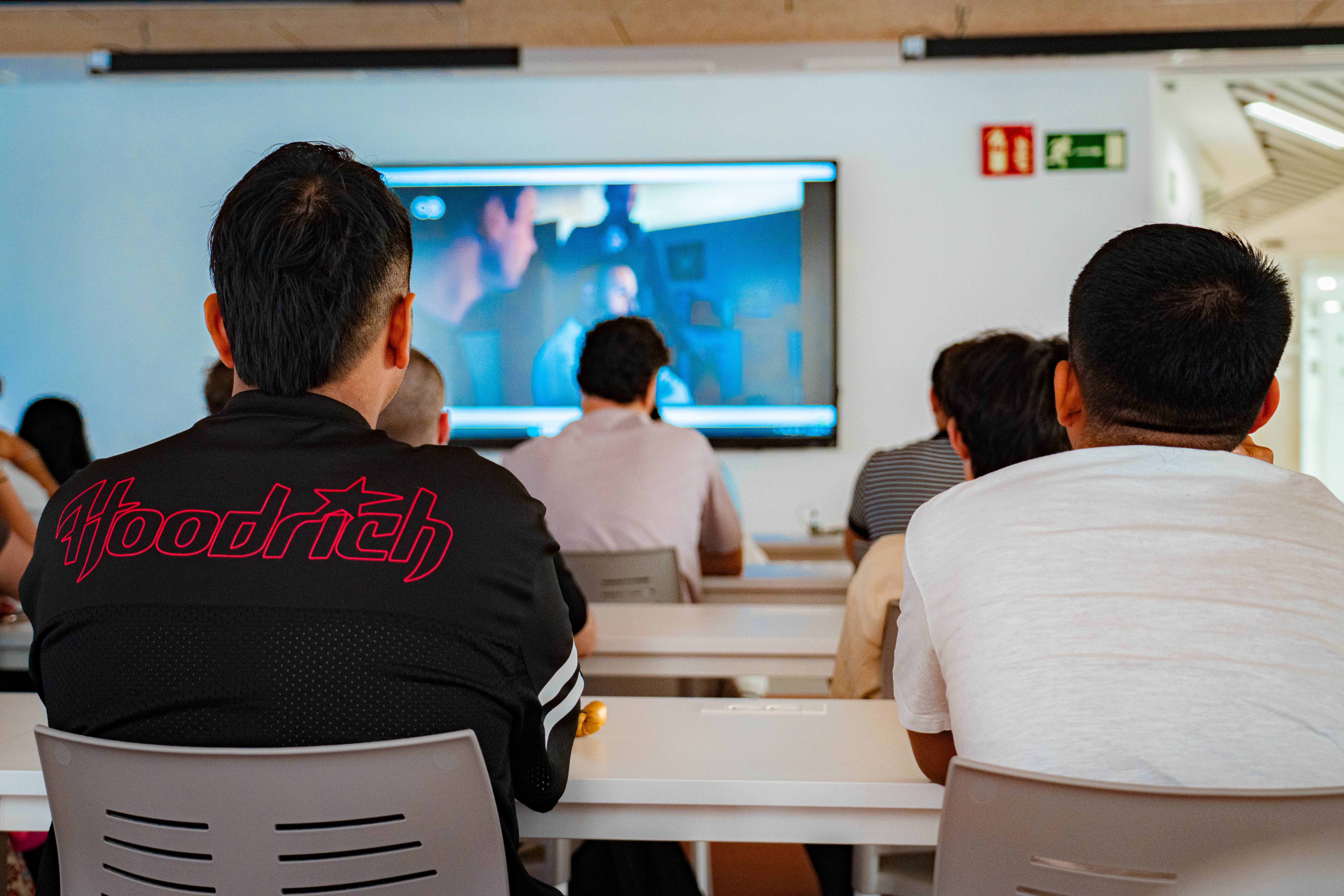 Un grupo de personas observando una presentación en una pantalla en un entorno académico.