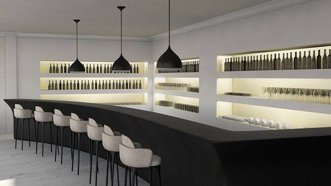 Un bar moderno con una barra negra y estanterías iluminadas que contienen botellas.