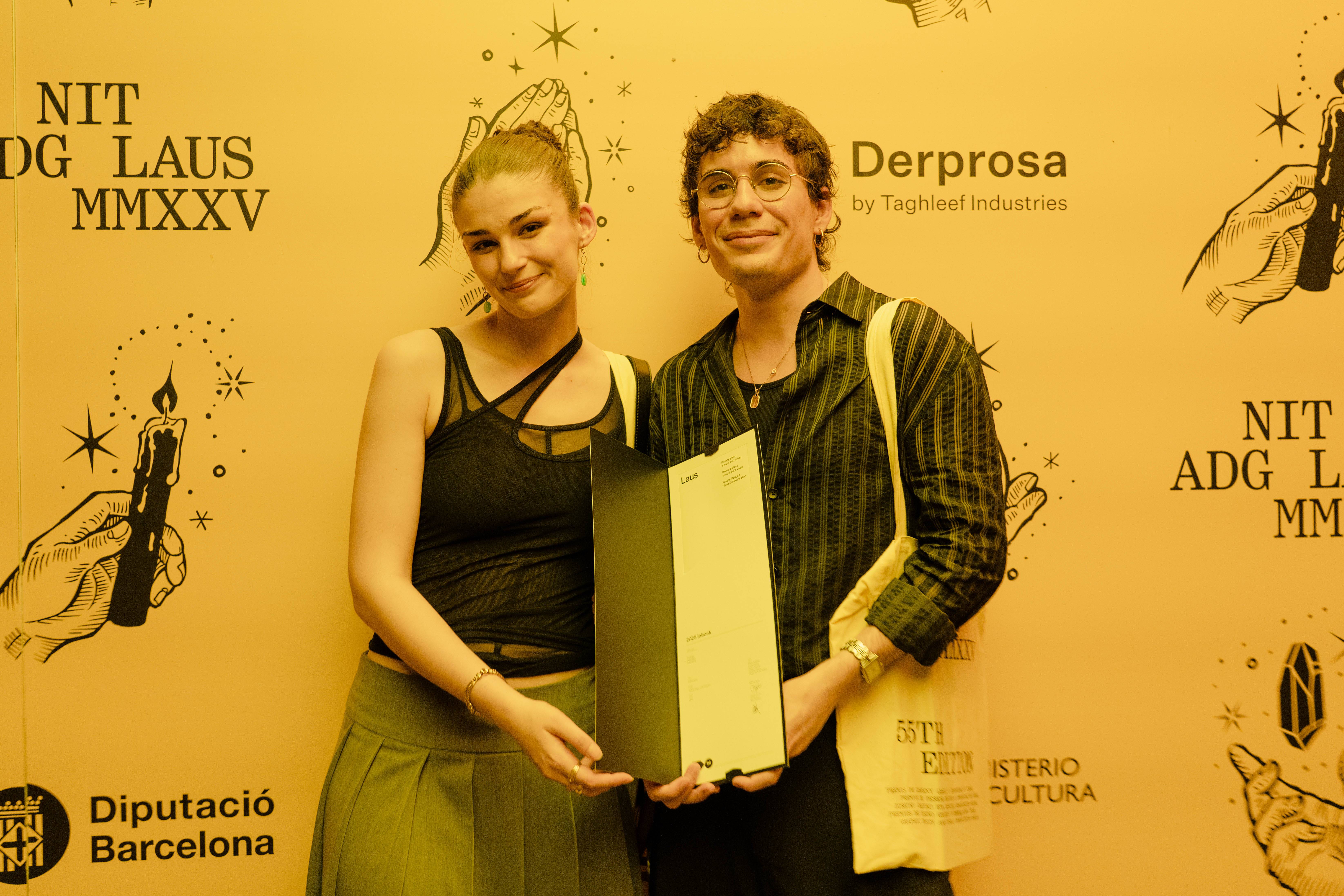 Dos personas posan sonrientes frente a un fondo decorado con velas y el texto de un evento.