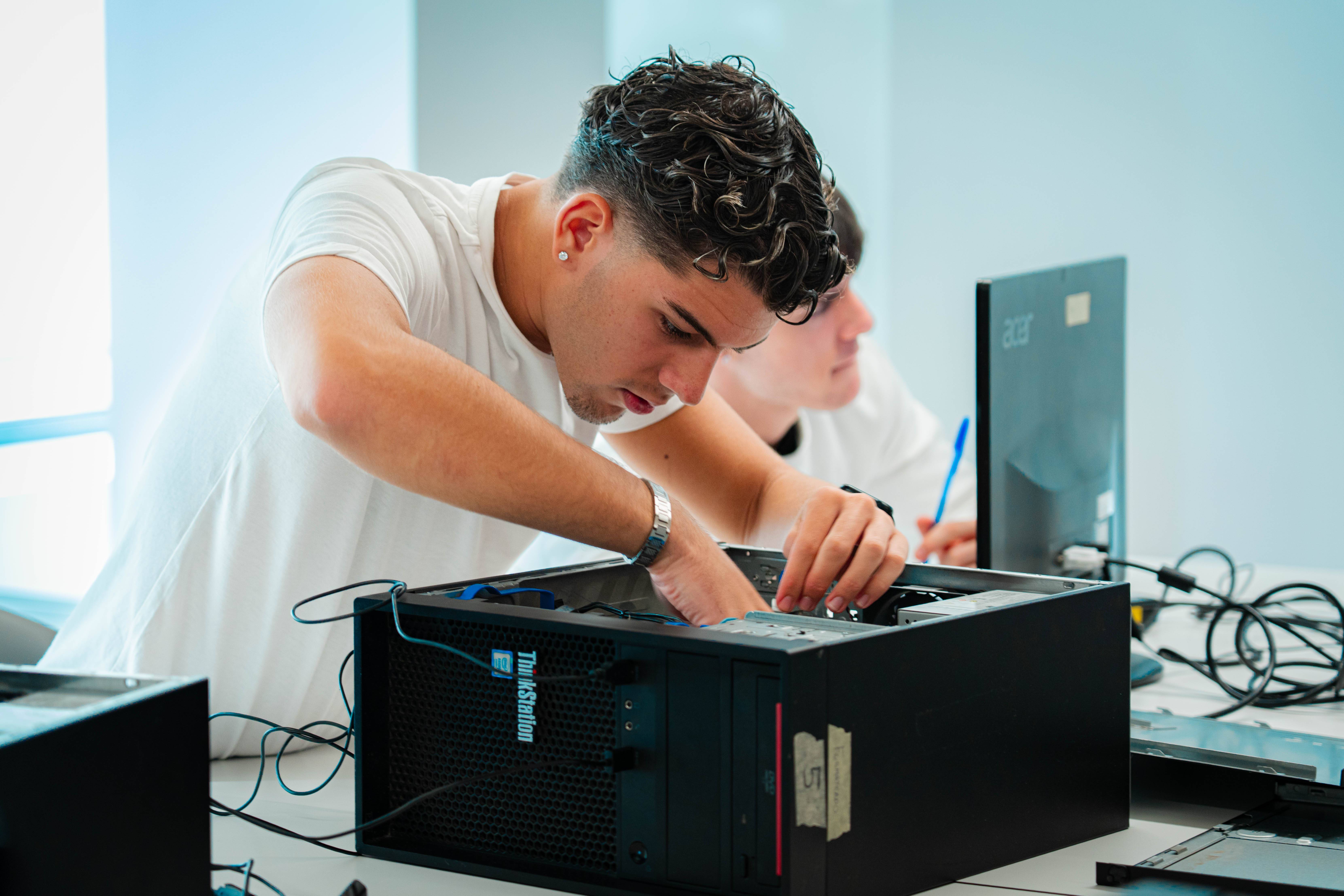 Un joven trabaja en el interior de un computador de escritorio en un entorno de aprendizaje.