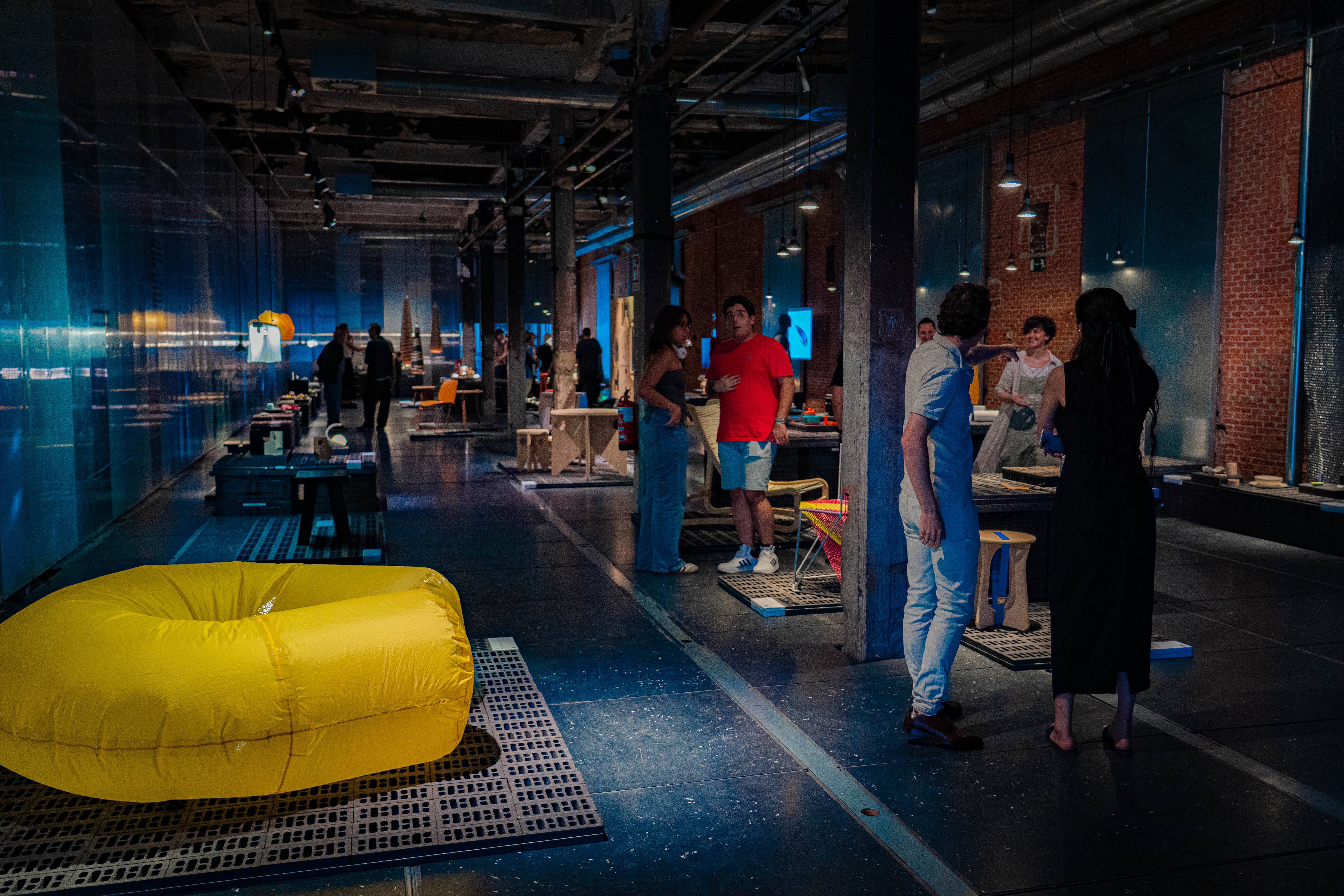 Una sala moderna llena de personas interactuando y muebles de diseño contemporáneo.