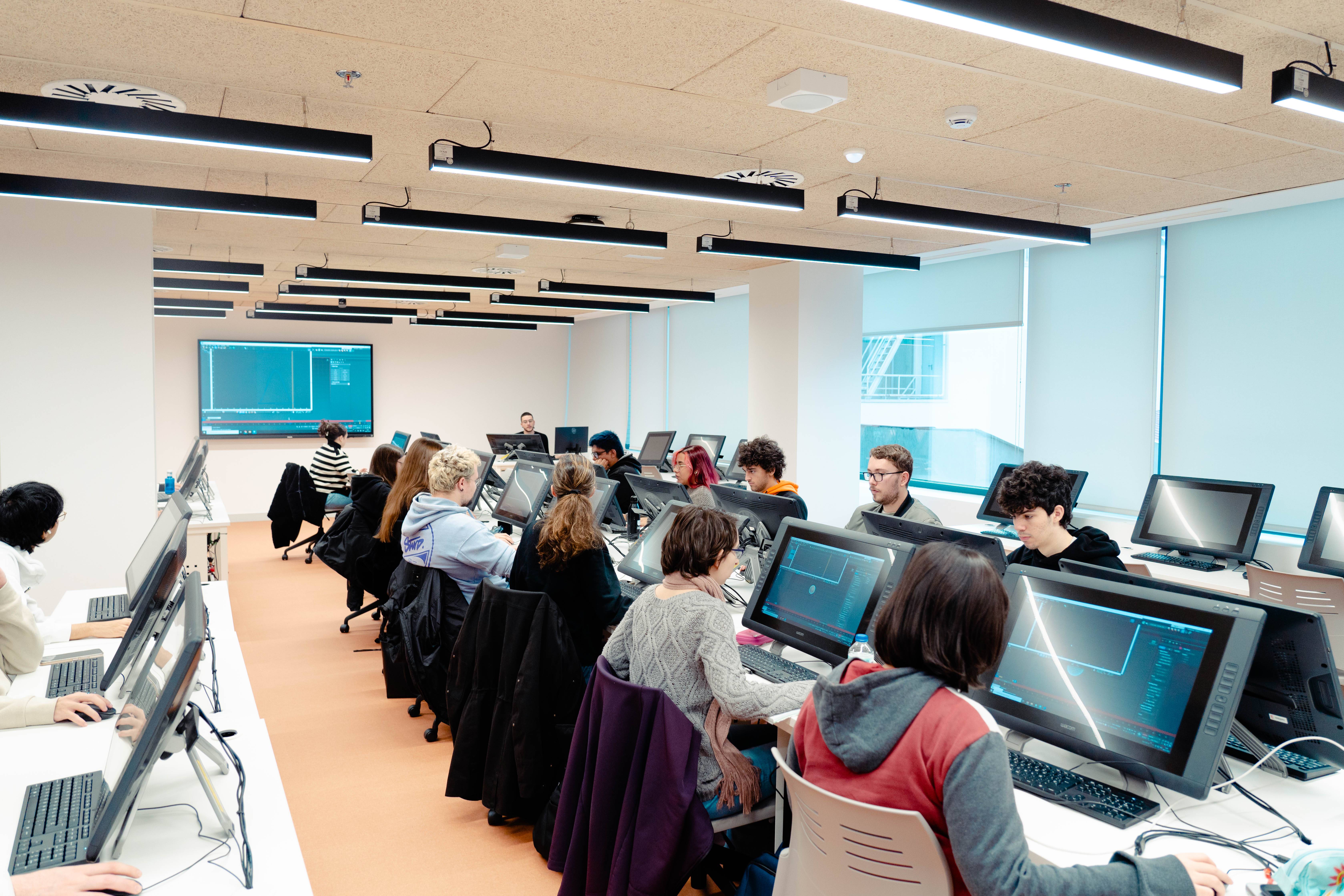 Un grupo de estudiantes trabaja en computadoras en un aula moderna.