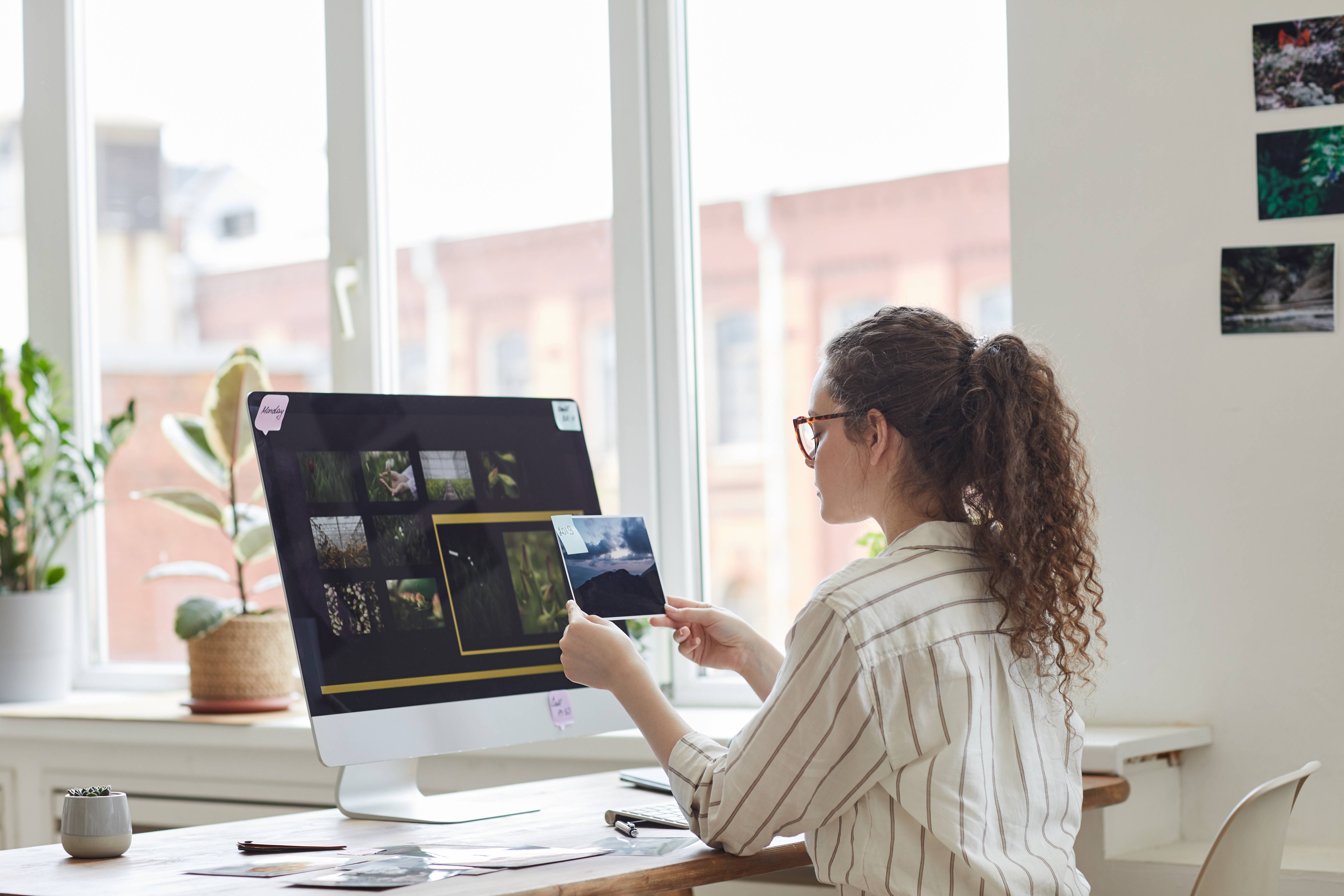 Una persona revisa imágenes en un monitor mientras sostiene una foto impresa.