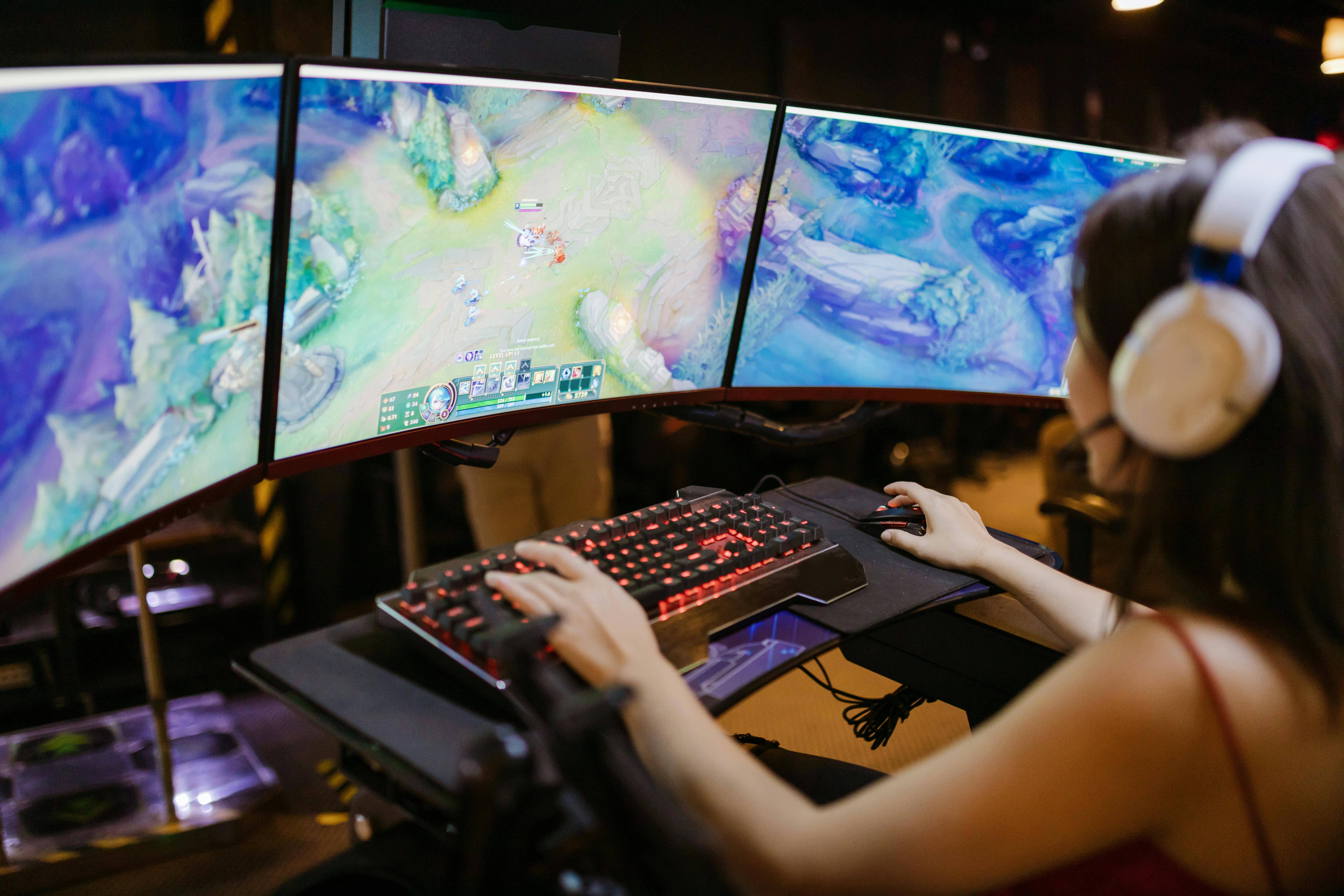 Una persona juega en un ordenador con múltiples pantallas mostrando un videojuego.