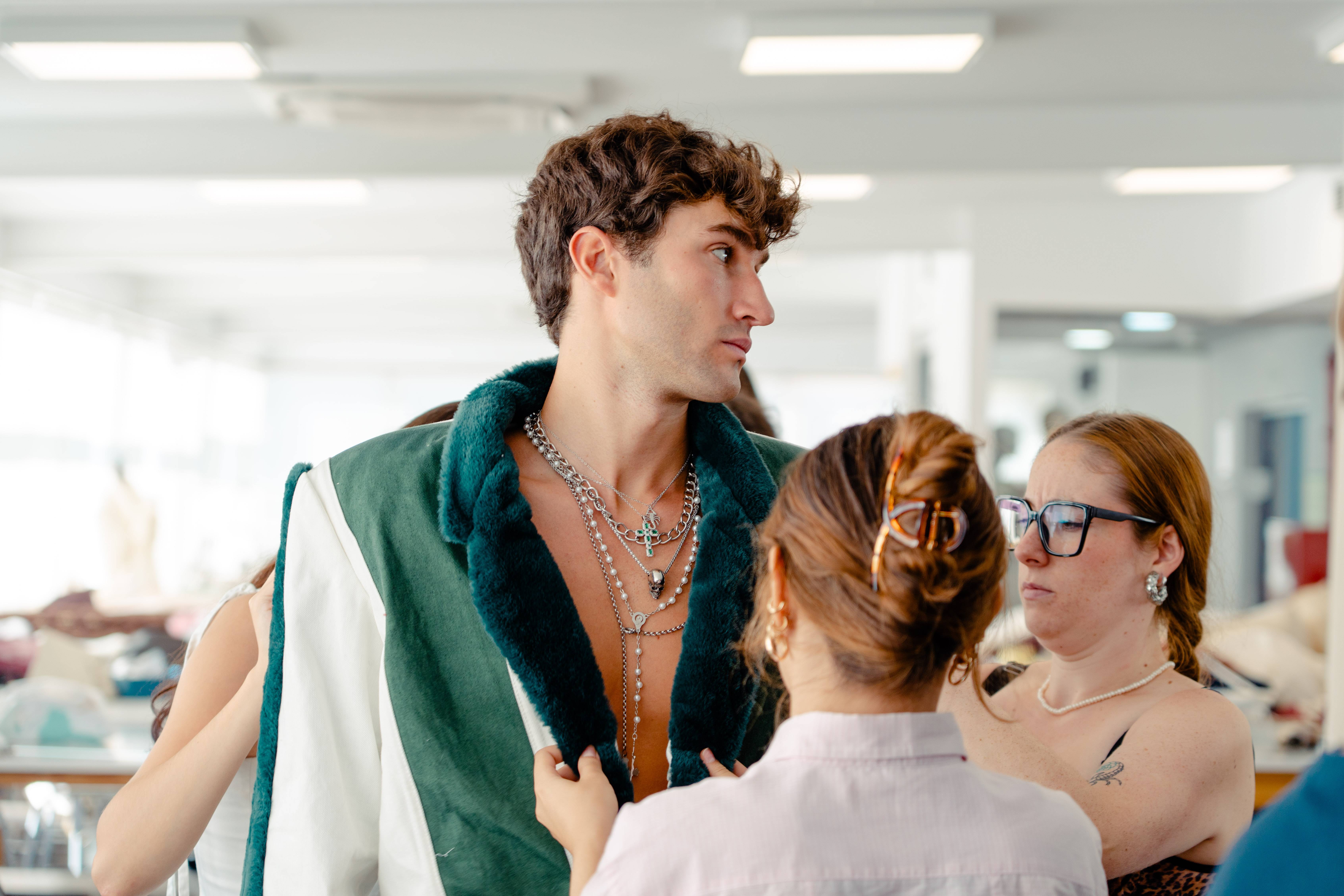 Un grupo de personas ayuda a un modelo a probarse una prenda de vestir en un taller de moda.
