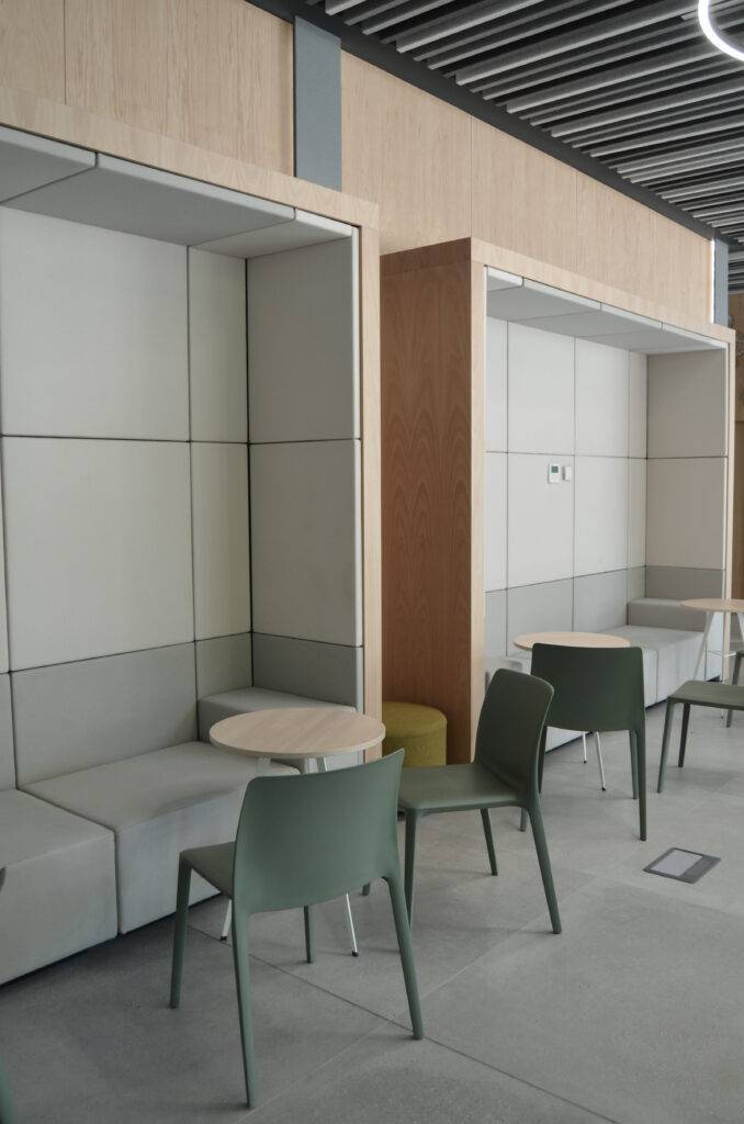 La imagen muestra un espacio moderno con asientos y mesas en un ambiente minimalista.