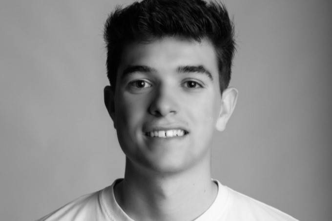 Retrato en blanco y negro de un joven sonriendo frente a la cámara.