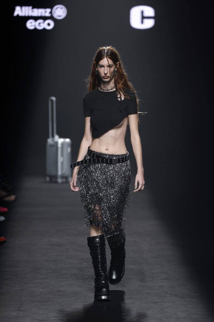 Modelo desfilando con un atuendo moderno y audaz en una pasarela de moda.