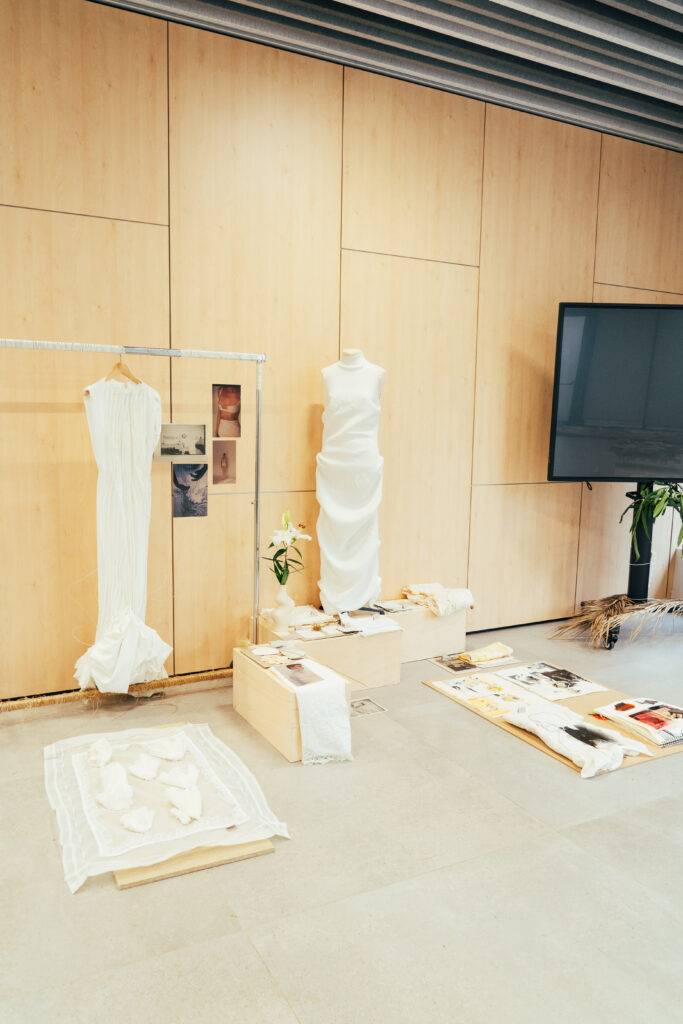 Una exposición de moda con vestidos blancos y materiales de diseño en un espacio moderno.
