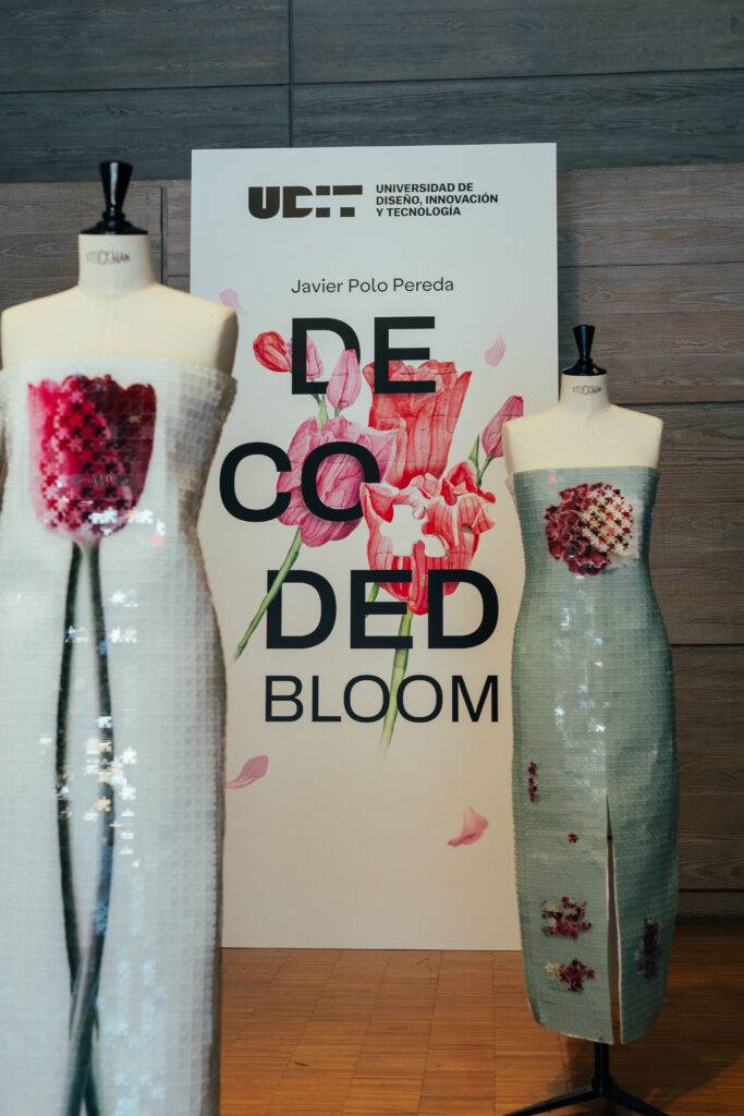 La imagen muestra dos vestidos de exhibición junto a un cartel que dice 'DECODED BLOOM'.