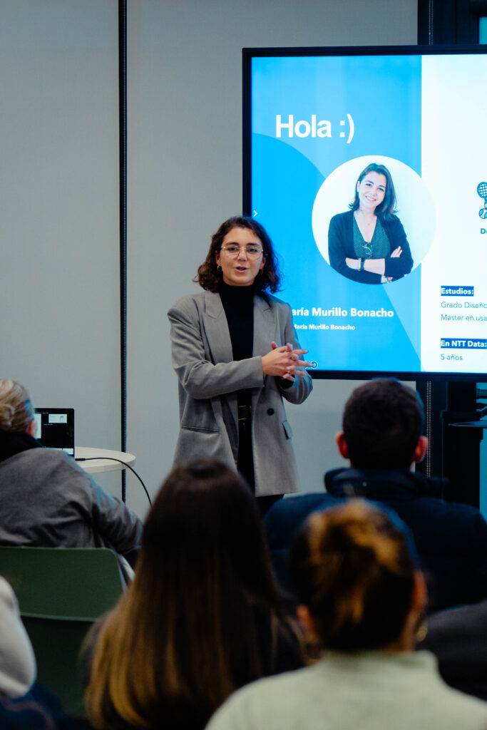 Una mujer está dando una presentación frente a un público en una sala moderna.
