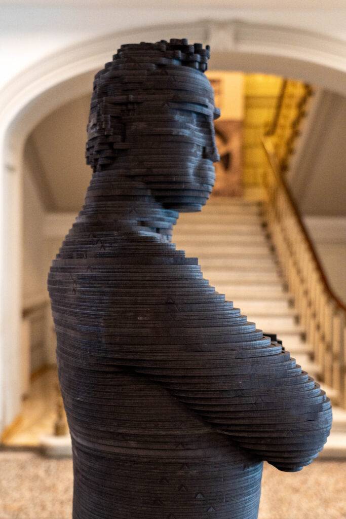 Escultura moderna de una figura humana en un espacio arquitectónico.