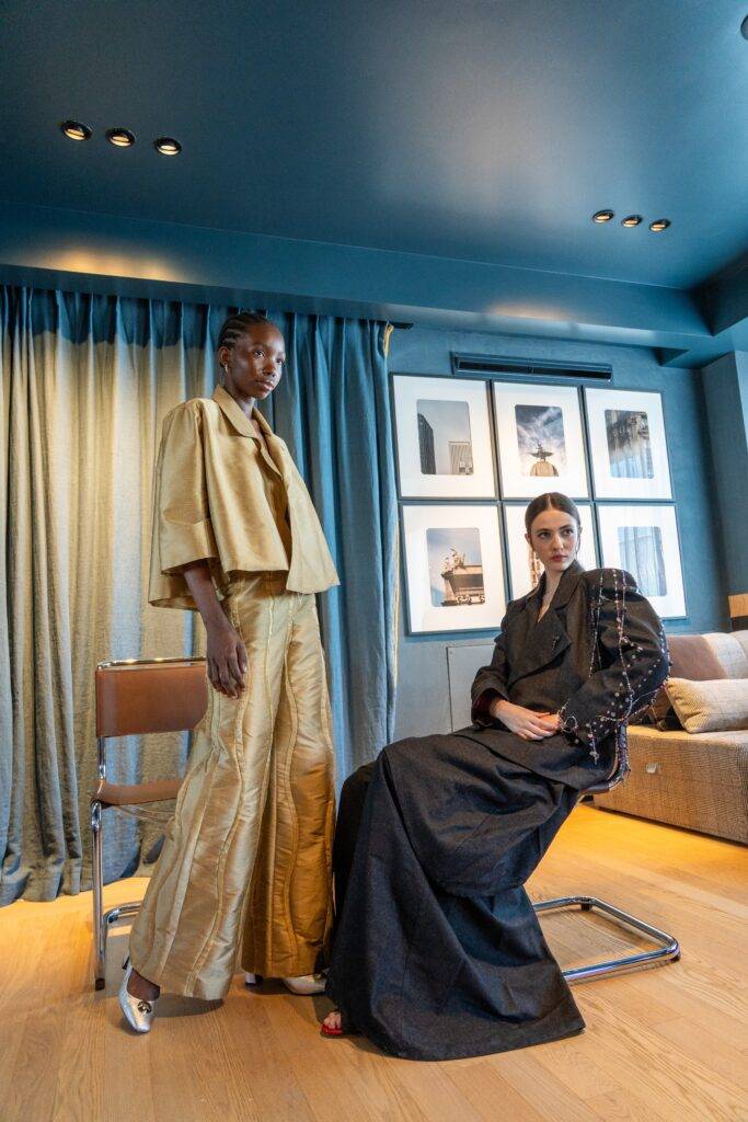Dos modelos posan en un ambiente elegante con ropa de moda en una habitación con decoración moderna.