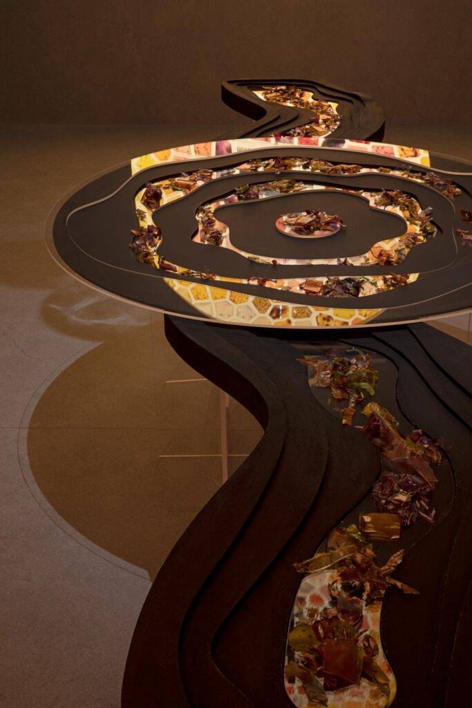 La imagen muestra una mesa artística con un diseño sinuoso y un patrón decorativo colorido.