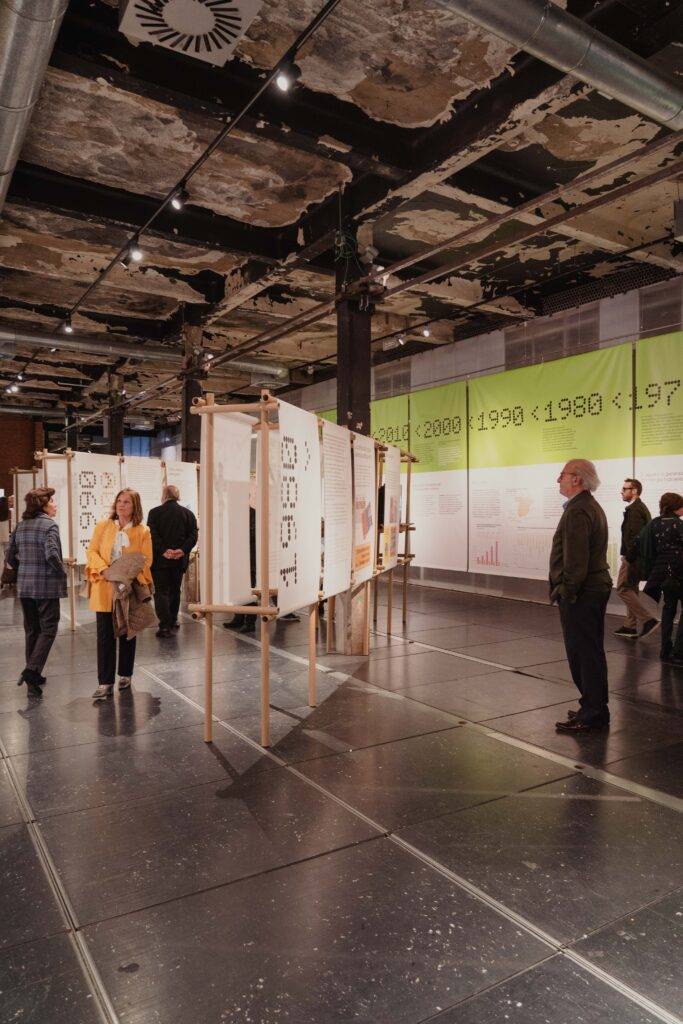 Una exposición en un espacio moderno con paneles informativos y visitantes observando.