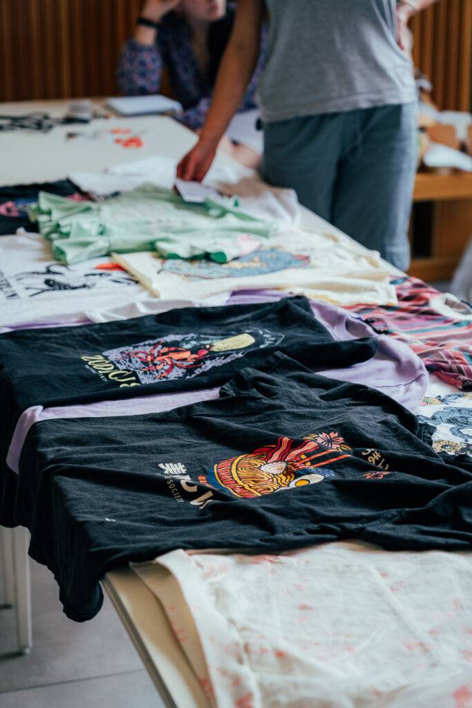 Una mesa con varias camisetas de diferentes colores y diseños dispuestas sobre ella.