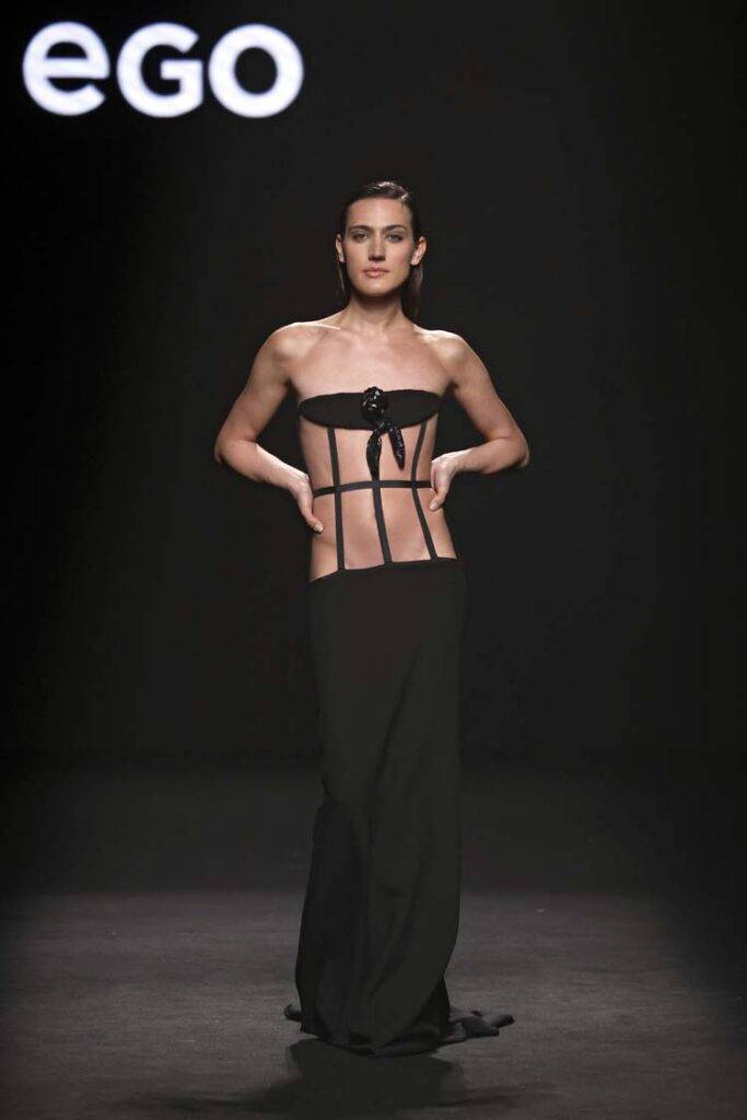 Modelo luciendo un vestido de noche negro durante una pasarela de moda.