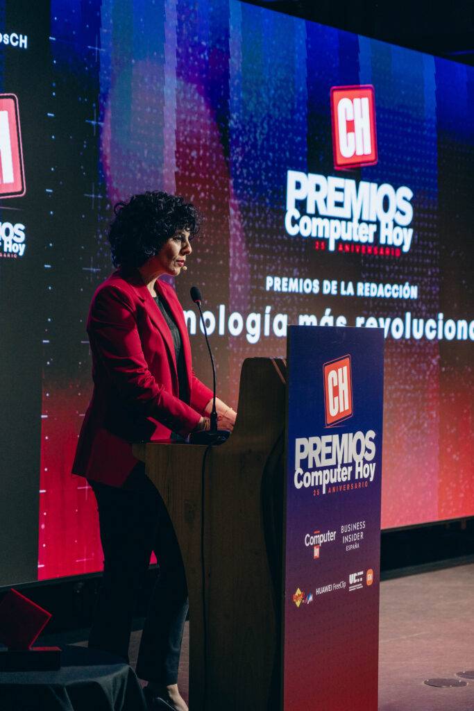 Una presentadora en un escenario habla frente a un podio en un evento de premios relacionados con la tecnología.