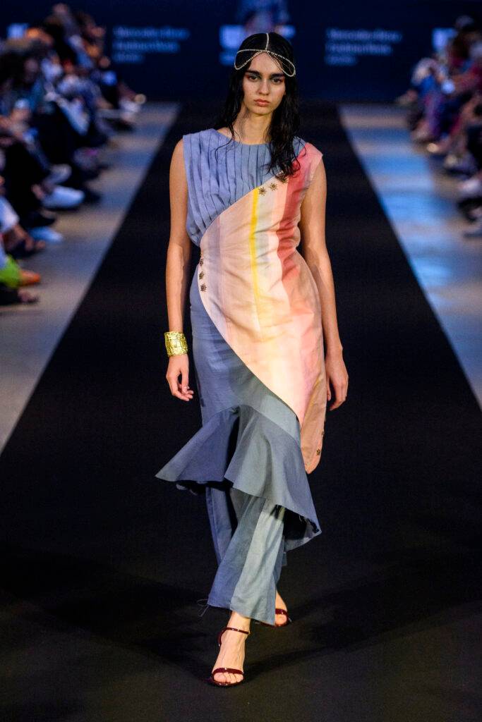 Una modelo desfila con un vestido de colores pastel en una pasarela.