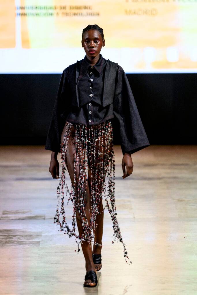 Una modelo camina por la pasarela vistiendo un atuendo moderno y audaz.