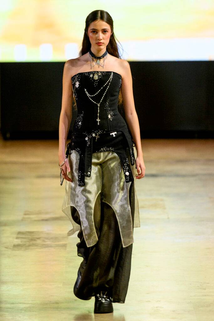 Modelo desfilando con un atuendo moderno y llamativo en la pasarela.