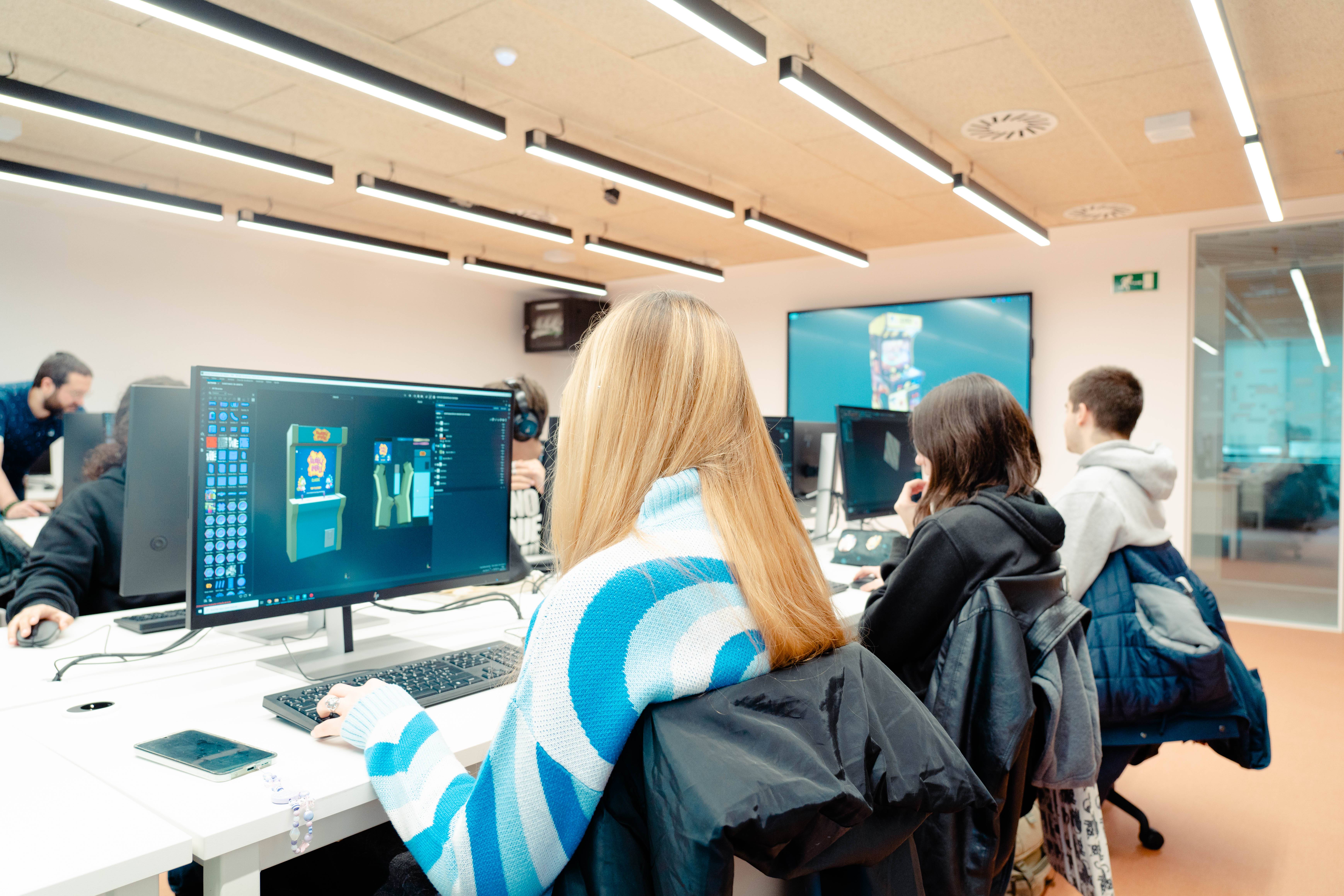 Un grupo de estudiantes trabajando en computadoras en un aula moderna.
