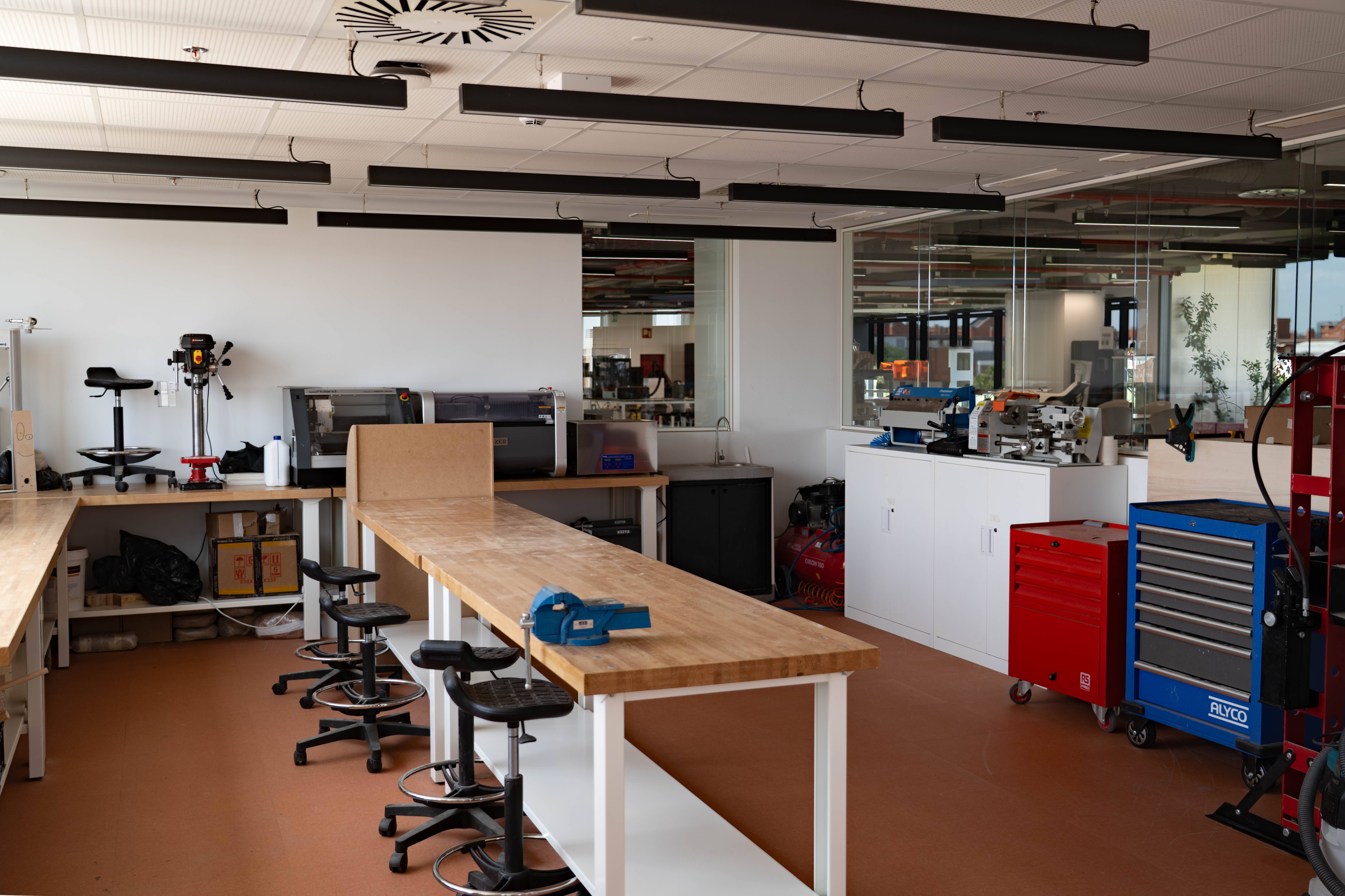 El interior de un taller moderno con mesas de trabajo y herramientas visibles.