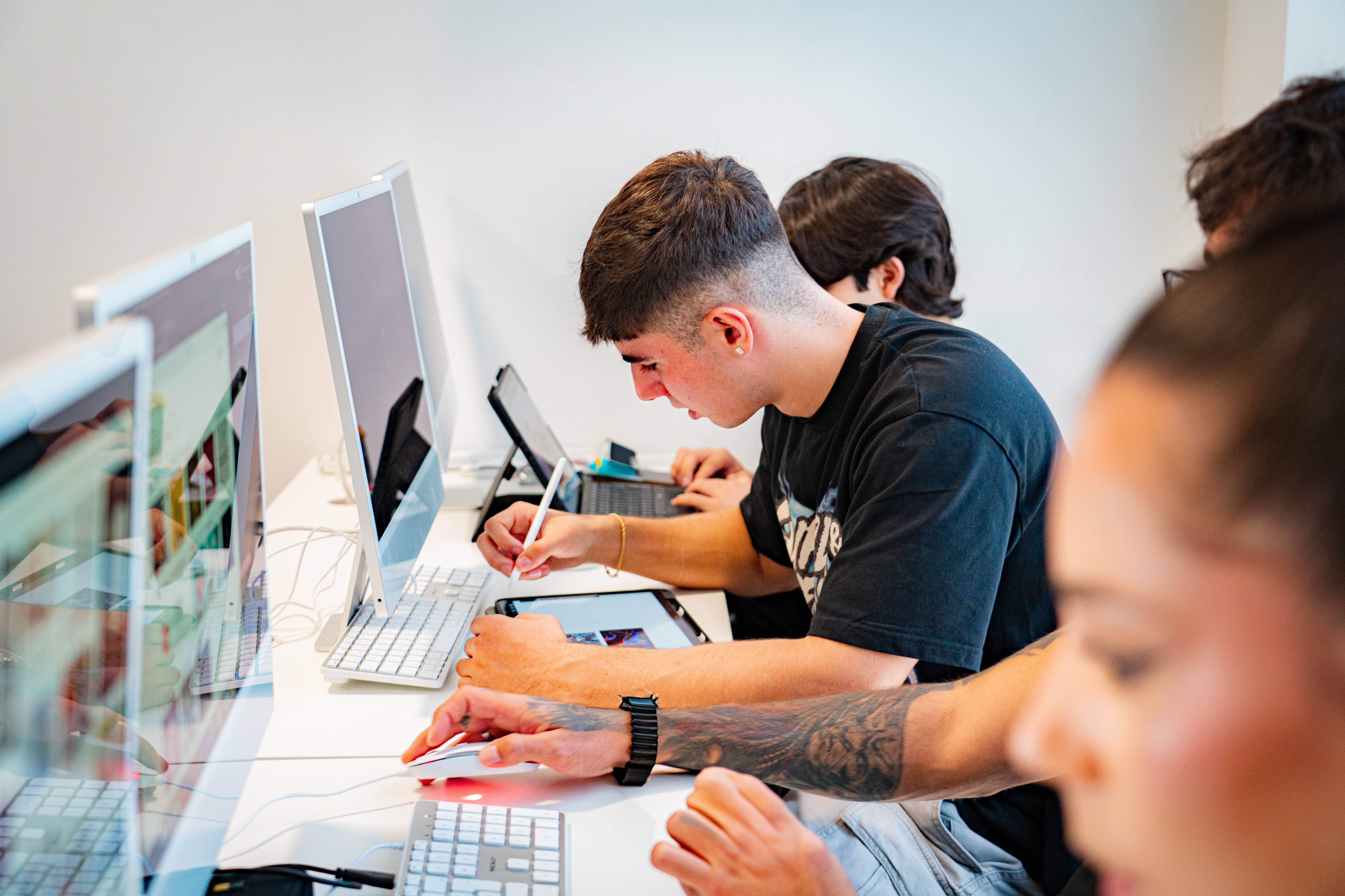 Un grupo de jóvenes trabajando en computadoras en un ambiente de estudio.