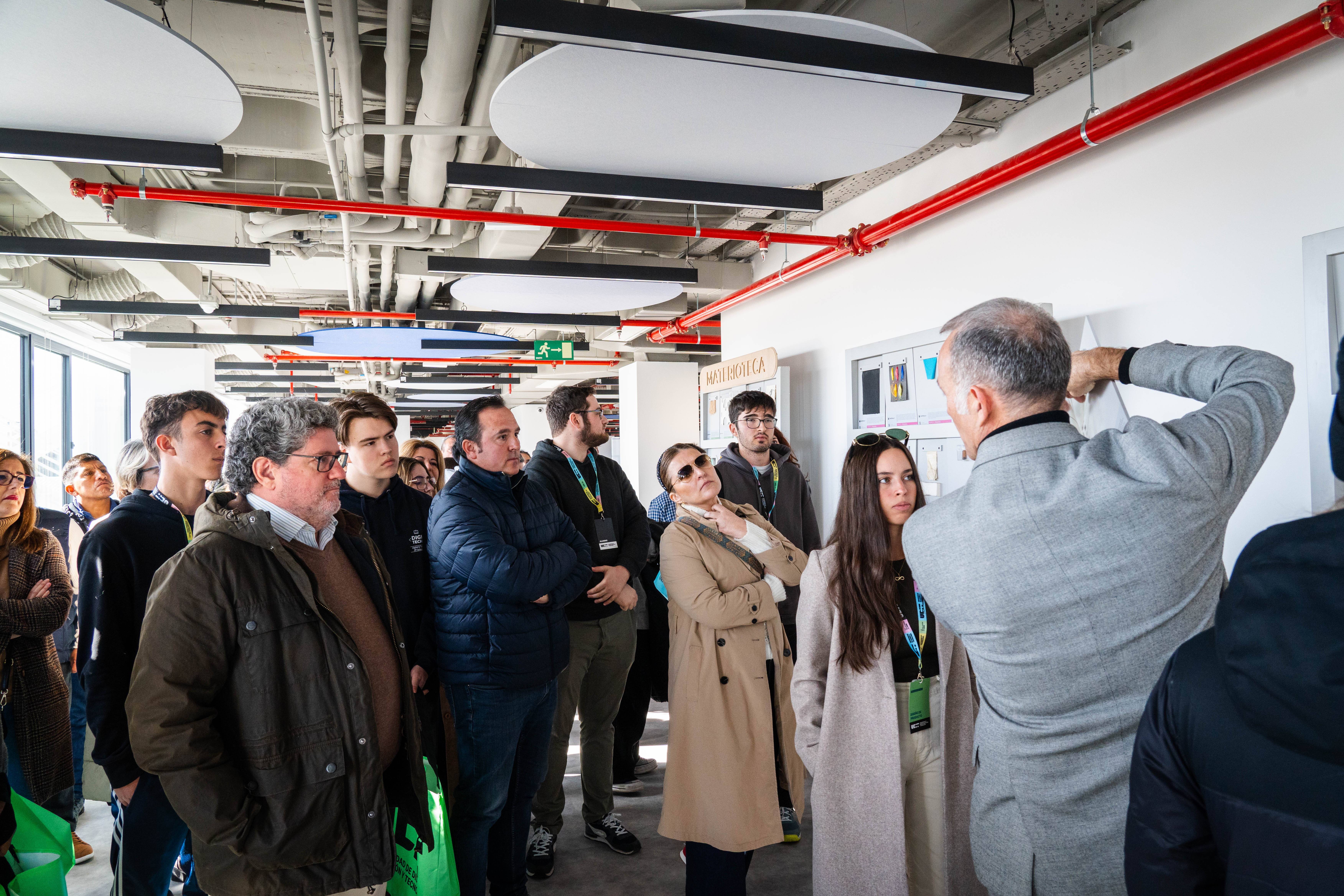 Un grupo de personas escucha atentamente a un presentador en un entorno urbano moderno.
