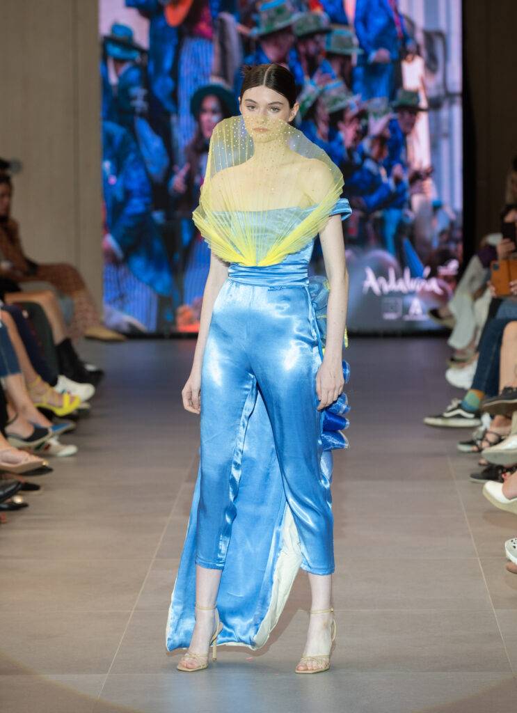 Modelo desfilando con un conjunto de ropa brillante en una pasarela.