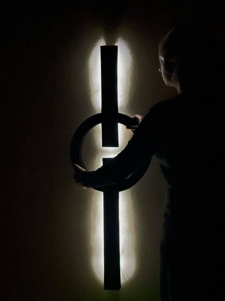 Una persona interactuando con una lámpara de diseño moderno en un ambiente iluminado de forma creativa.