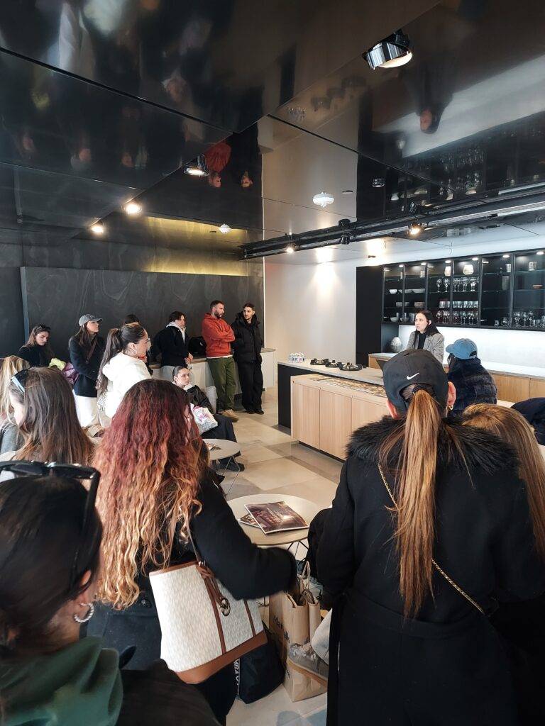Un grupo de personas está esperando en una tienda moderna, con una mujer detrás del mostrador.