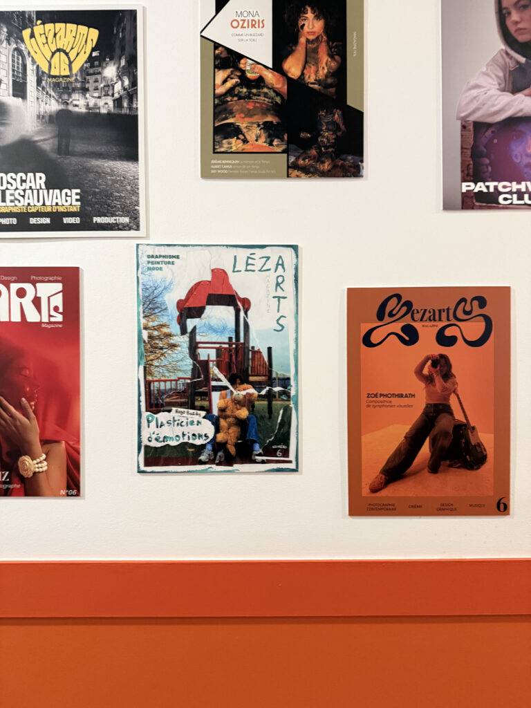 Una colección de carteles artísticos en una pared, destacando uno en el centro que dice 'LÉZARTS'.