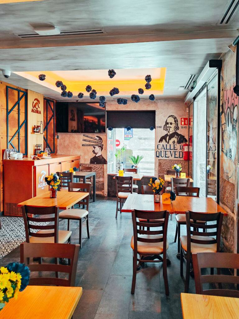 Un interior de restaurante acogedor con mesas de madera y flores en los centros de mesa.