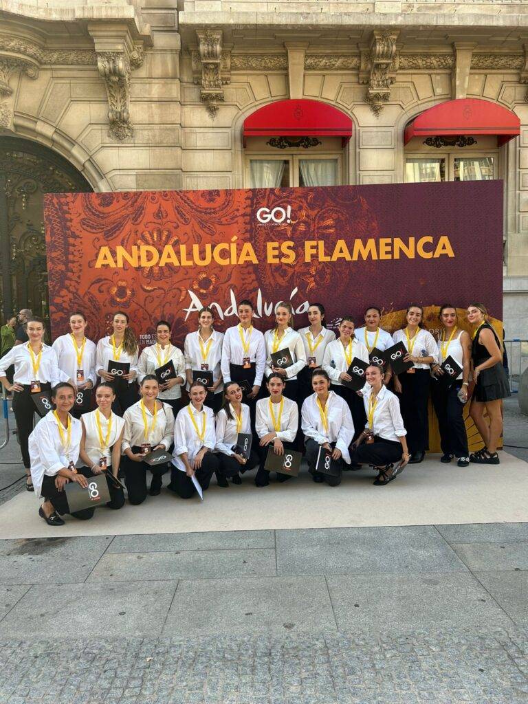 Grupo de bailarines vestidos de flamenco en un evento dedicado a la cultura andaluza.