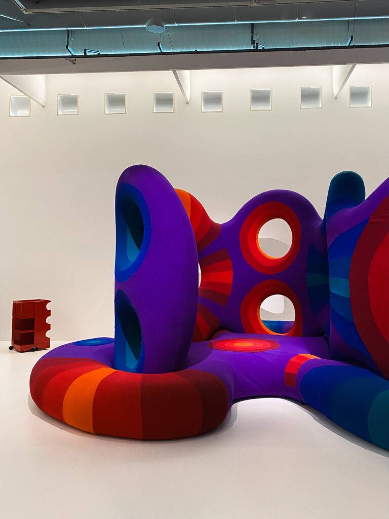 Una instalación artística colorida y orgánica con formas sinuosas y suaves en un entorno minimalista.