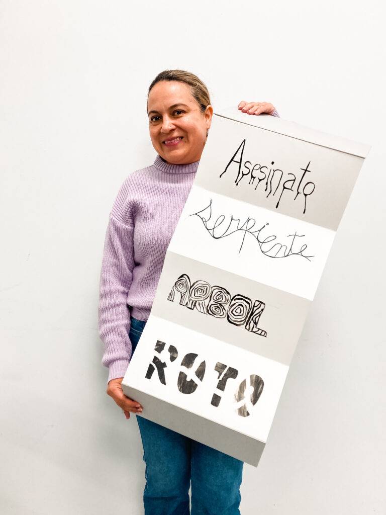 Una mujer sostiene un cartel con varias palabras artísticamente escritas.