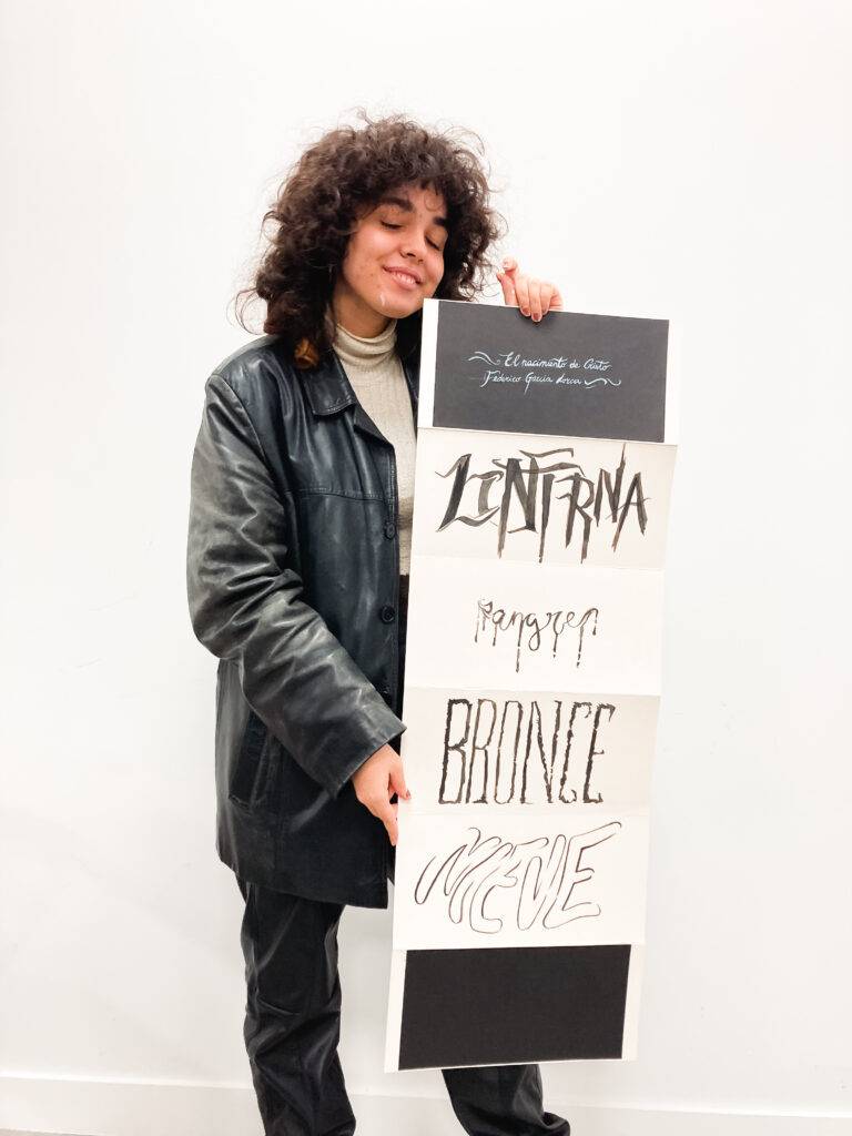 Una joven sostiene un cartel con diversas palabras en diferentes estilos de escritura.