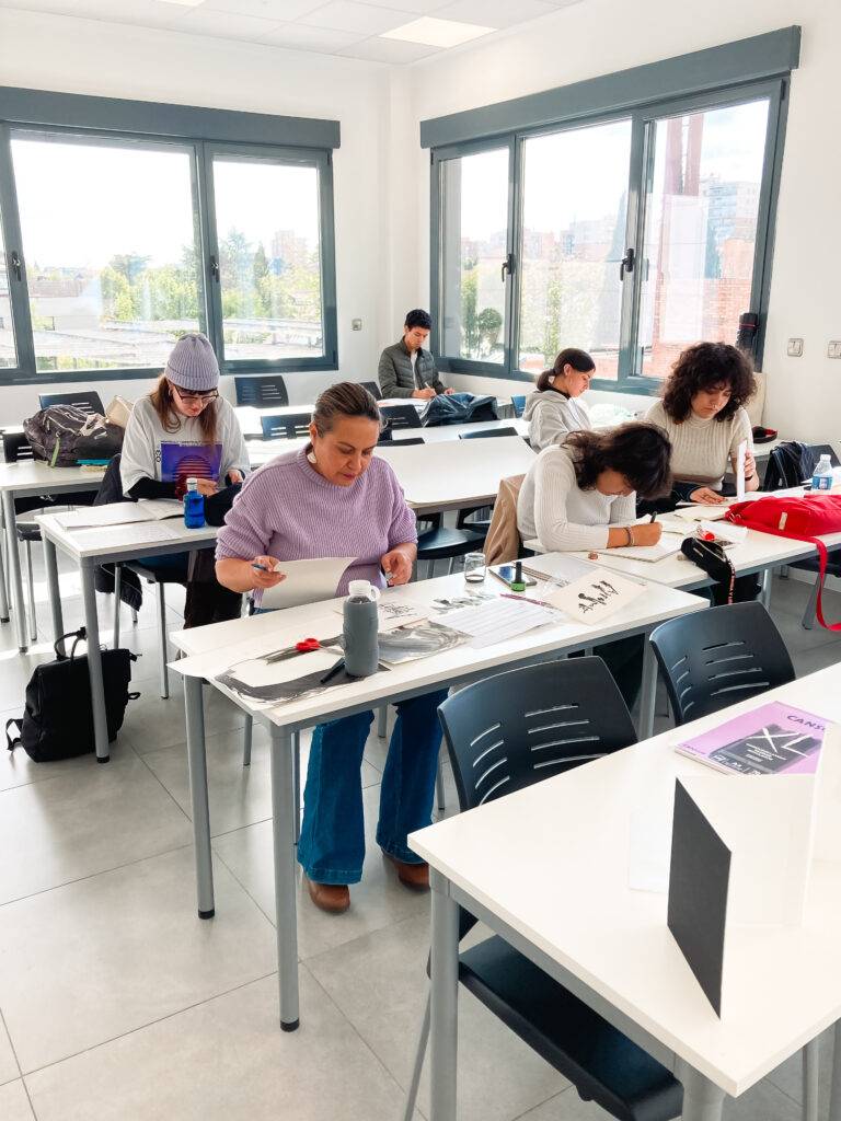 Un aula con varios estudiantes trabajando en sus proyectos artísticos.