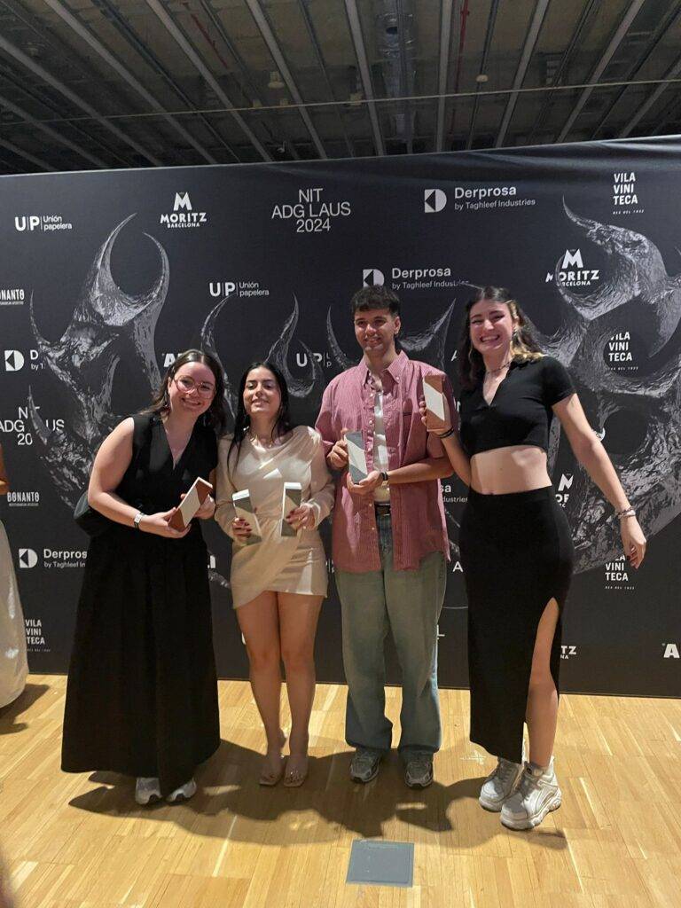 Un grupo de cuatro personas sonríen mientras sostienen premios en un evento.