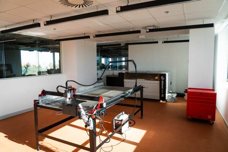 Un espacio de oficina moderno con una máquina de corte láser en el centro.
