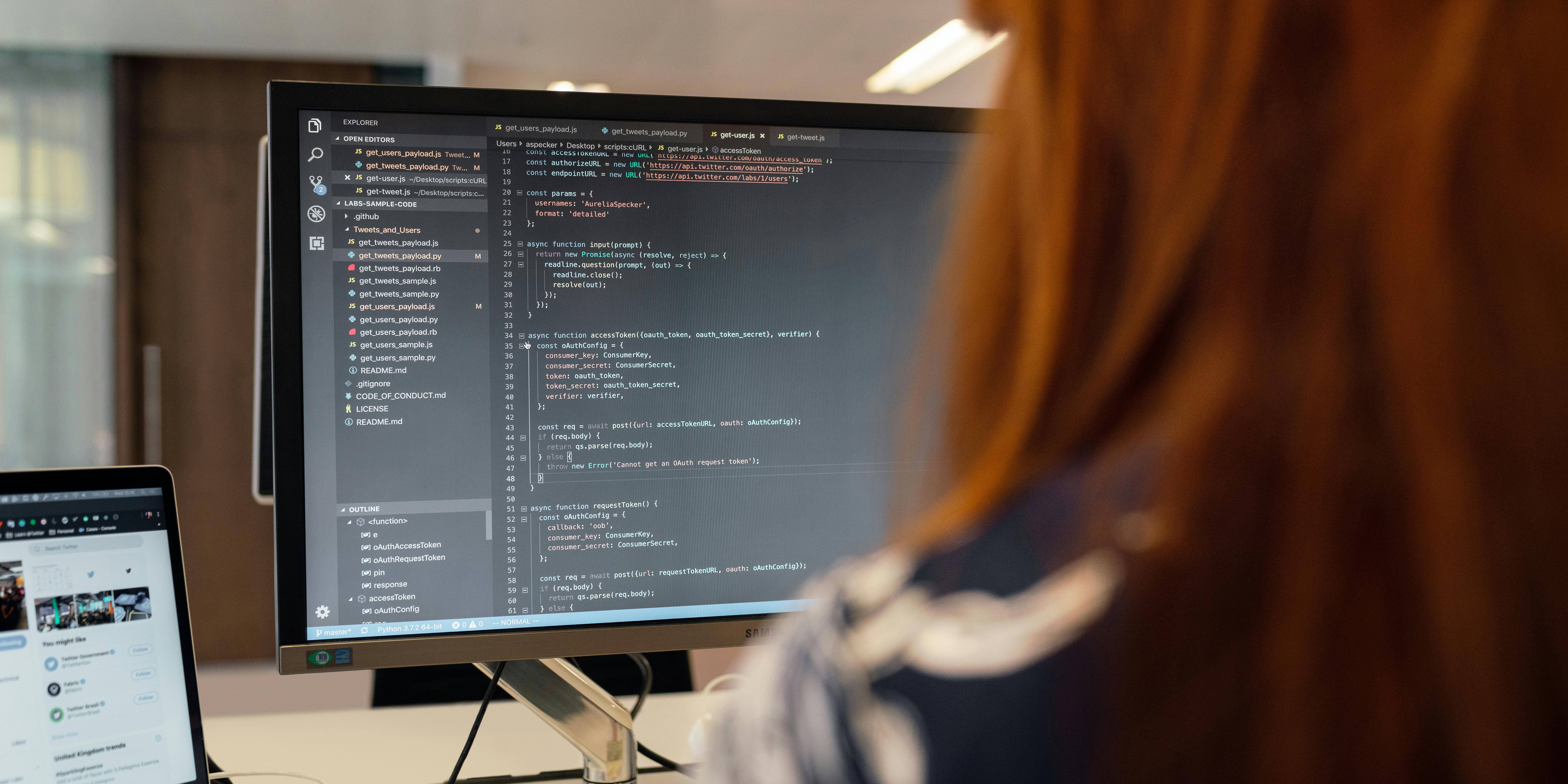 Una persona trabajando en programación frente a una computadora con código en la pantalla.