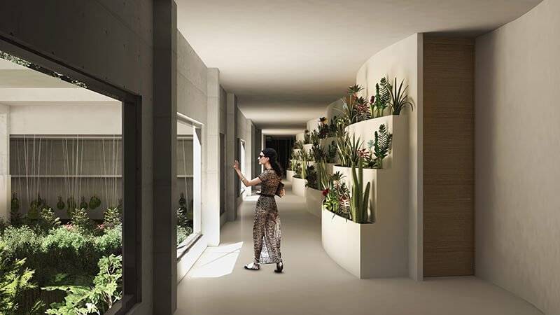 Una mujer observa un pasillo moderno con paredes de concreto y plantas decorativas.