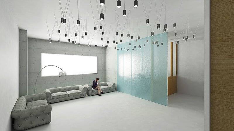 Una moderna sala de espera con sofás grises y paneles de vidrio en un ambiente minimalista.