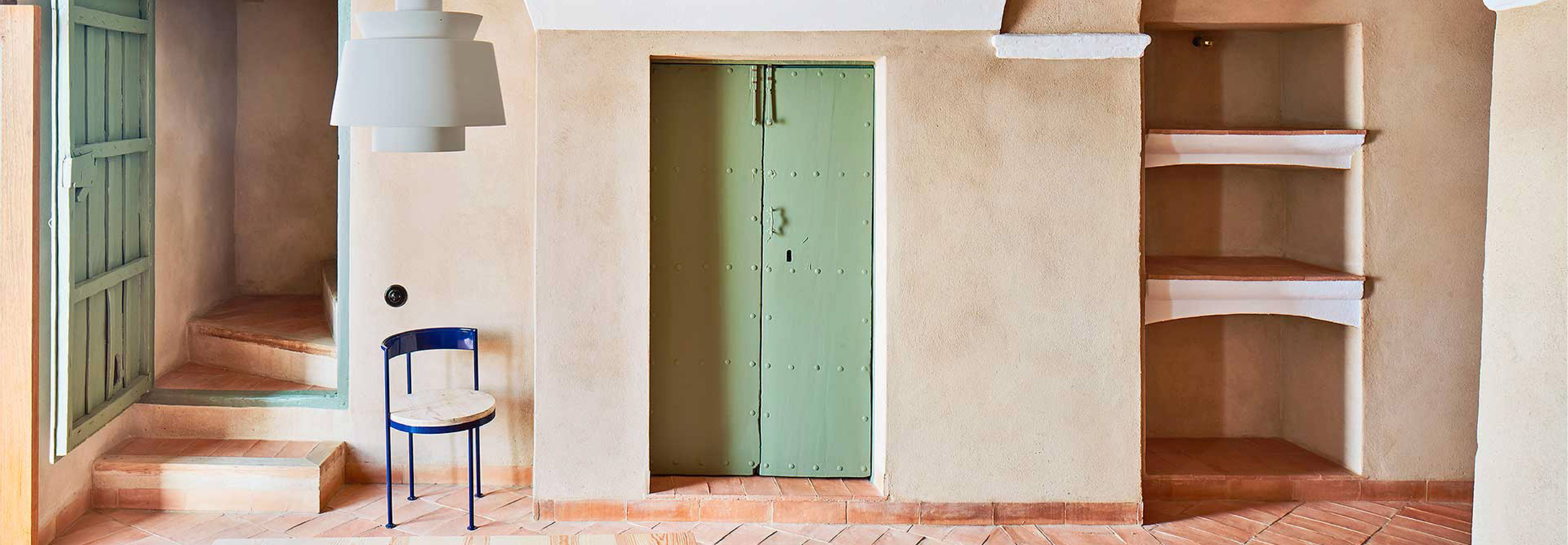 Una habitación con paredes de tonos suaves y una puerta verde que da acceso a otro espacio.