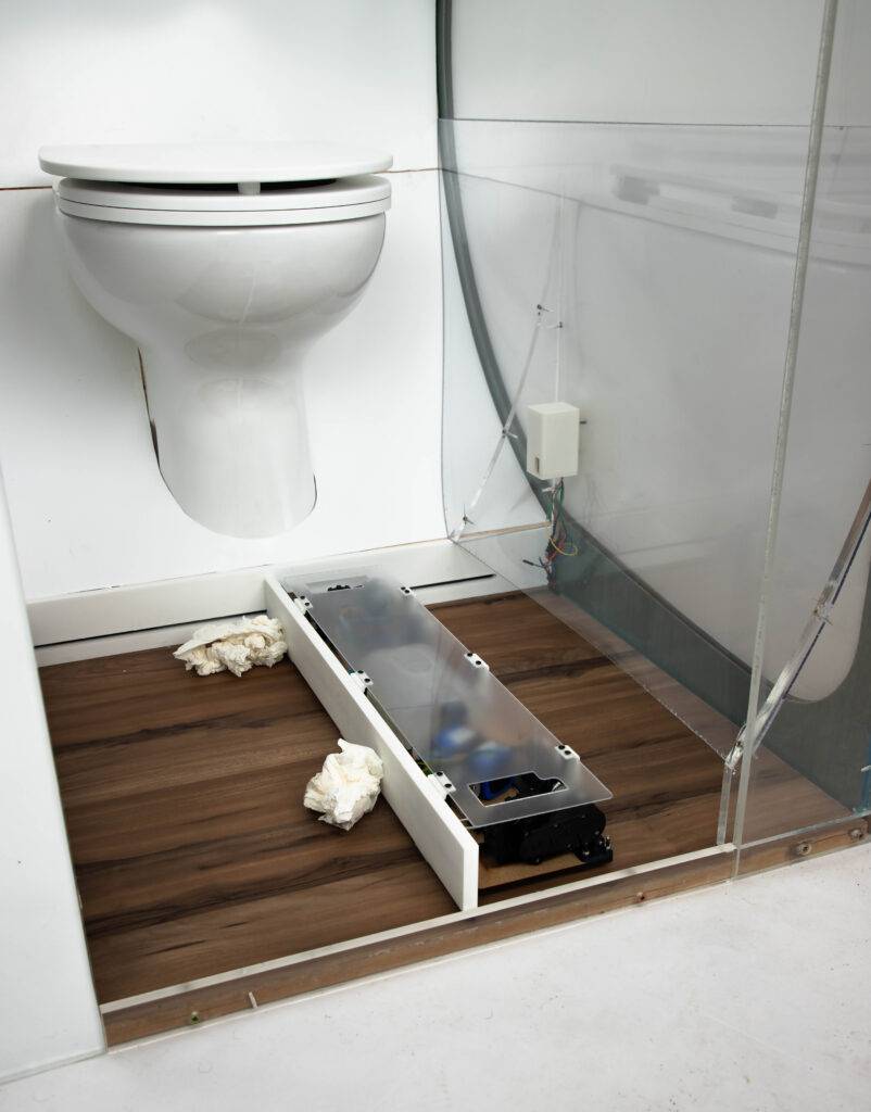 Un baño moderno con inodoro y un área de piso de madera clara.
