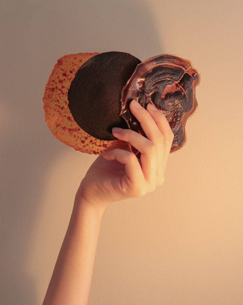 Una mano sostiene tres pancakes apilados con diferentes colores y texturas.